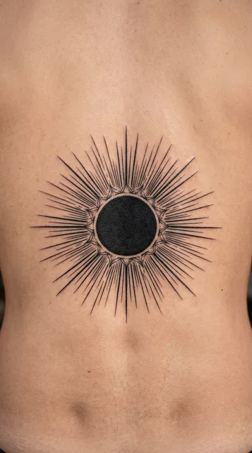 Black and white blackwork sun tattoo on a man's back