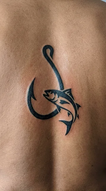 Black and white tribal fish tattoo on a man's back