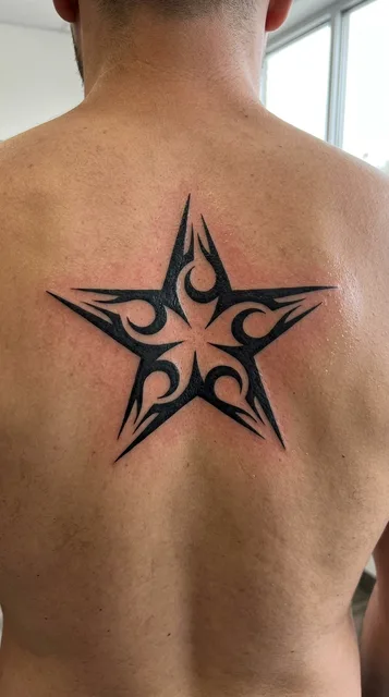 Black and white tribal star tattoo on a man's back