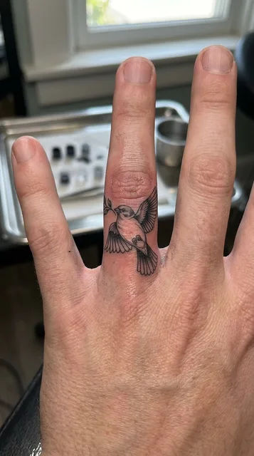 Black and grey dotwork bird tattoo on a man's finger