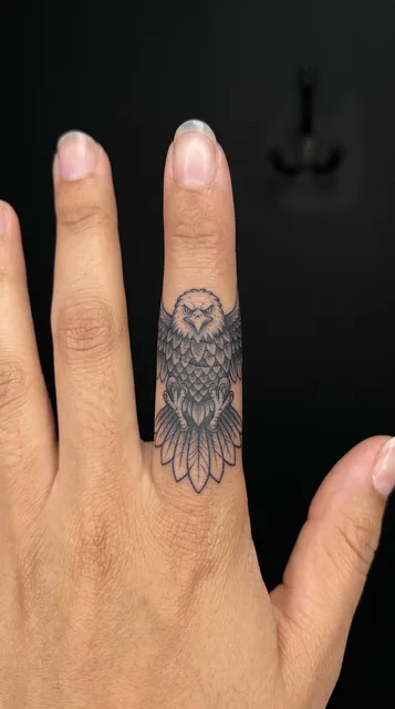 Black and grey illustrative eagle tattoo on a woman's finger