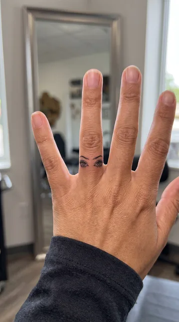 Black and white linework eyes tattoo on a woman's finger