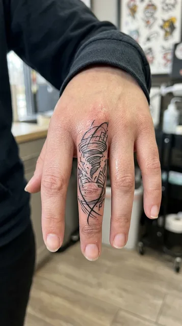 Black and white linework face tattoo on a woman's finger