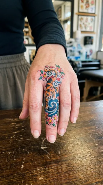Color Japanese cat tattoo on a woman's finger
