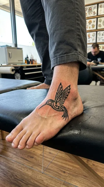 Black and white tribal hummingbird tattoo on a man's foot