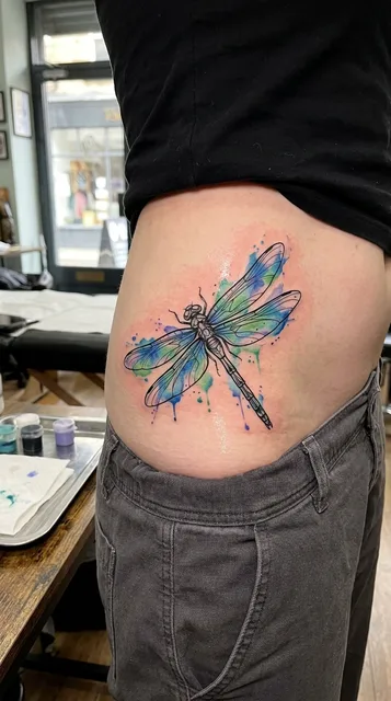 Color watercolor dragonfly tattoo on a woman's hip