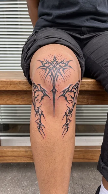 Black and white tribal ornament tattoo on a woman's knee
