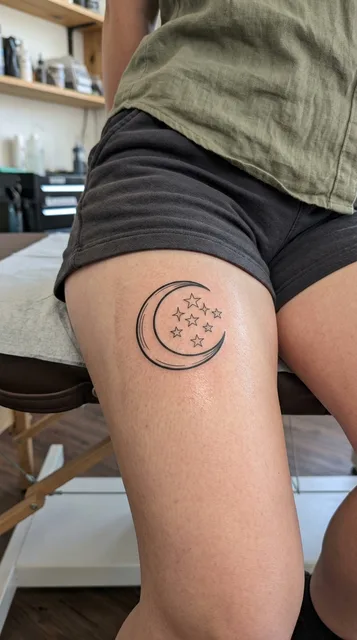 Black and grey illustrative moon tattoo on a woman's thigh