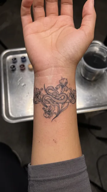 Black and grey dotwork snake tattoo on a woman's wrist
