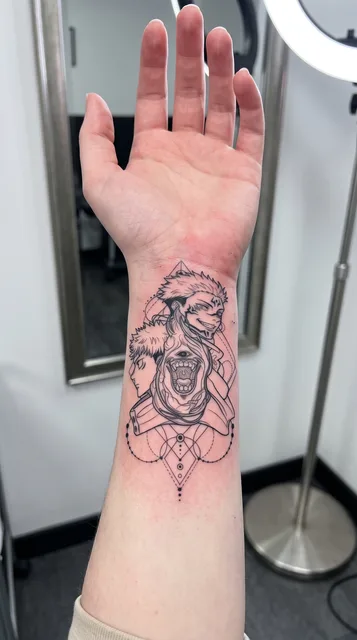 Black and grey illustrative faces tattoo on a woman's wrist